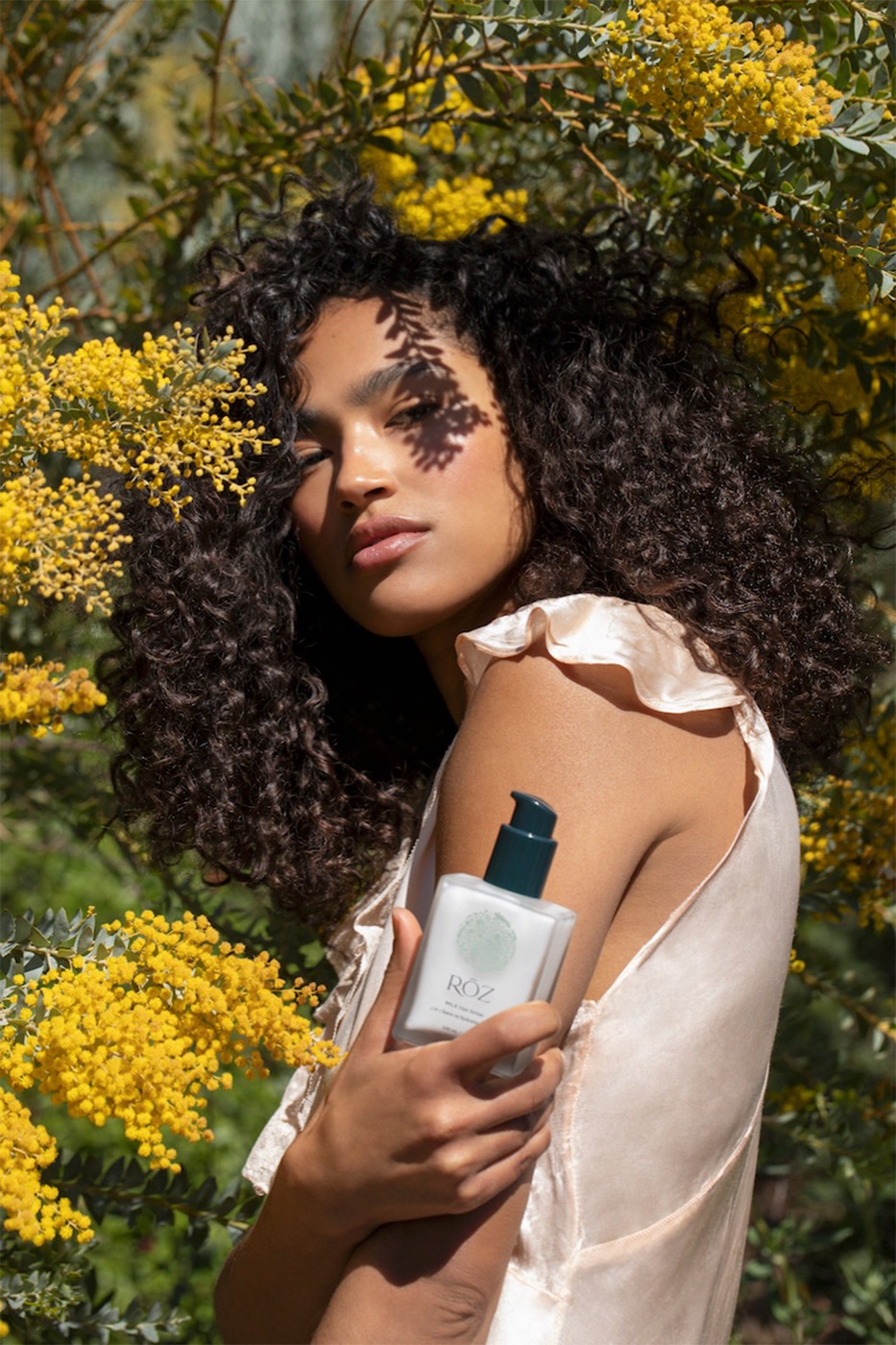Model holding RŌZ Milk Hair Serum outdoors